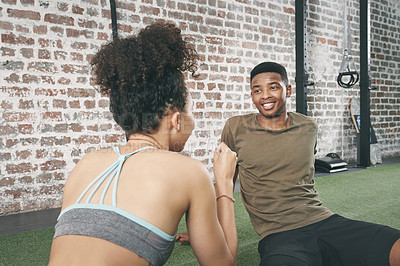 Buy stock photo Shot of two sporty young people having a conversation while sitting together at the gym
