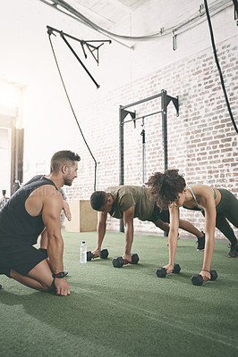 Buy stock photo Shot of two people working out with a fitness instructor at the gym