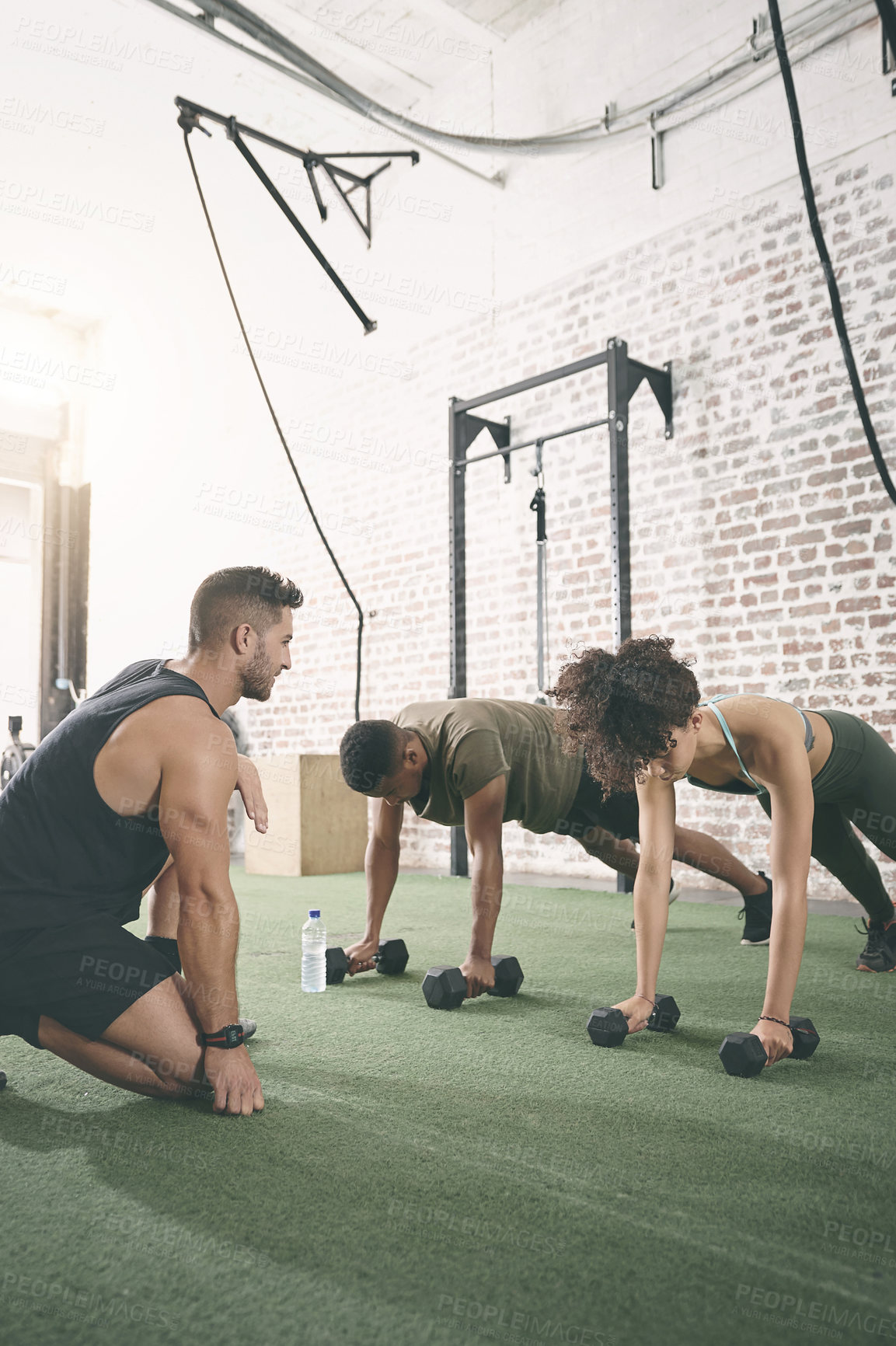 Buy stock photo Shot of two people working out with a fitness instructor at the gym