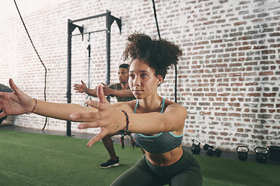 Buy stock photo Shot of two sporty young woman doing squats at the gym