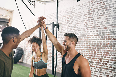 Buy stock photo Shot of three sporty young people giving each other a high five