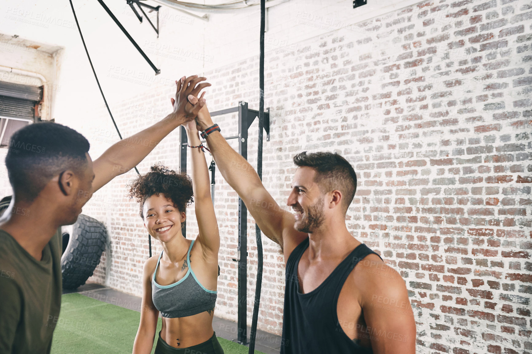 Buy stock photo Shot of three sporty young people giving each other a high five