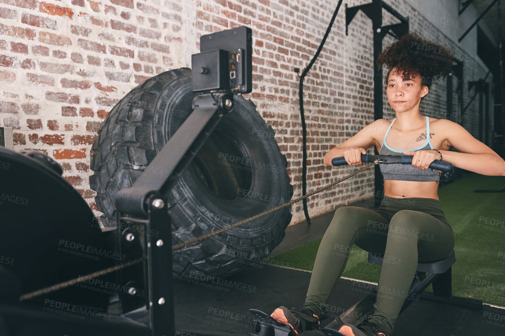 Buy stock photo Shot of a sporty young woman working out on a rowing machine