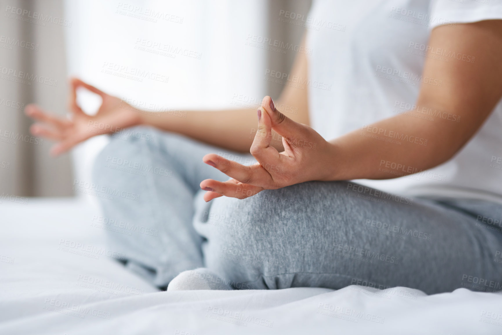 Buy stock photo Cropped shot of a young woman meditating by herself on top of her bed at home