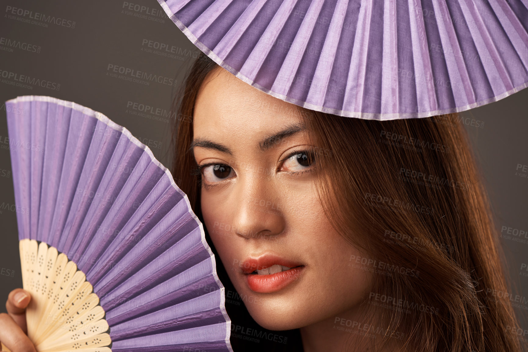 Buy stock photo Cropped portrait of an attractive young woman posing with fans in studio against a grey background