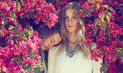 Buy stock photo Shot of a young couple standing together under a flowering bush