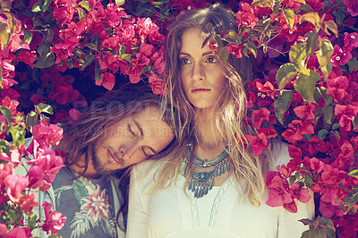 Buy stock photo Shot of a young couple standing together under a flowering bush