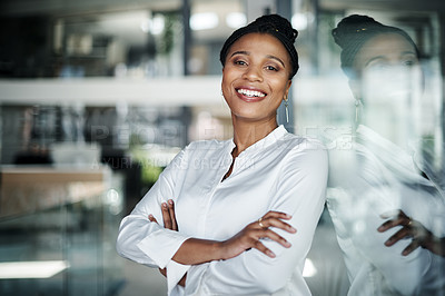 Buy stock photo Shot of an attractive young businesswoman standing alone in the office with her arms folded during the day