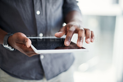 Buy stock photo Cropped shot of an unrecognizable businessman standing alone in his office and using a digital tablet