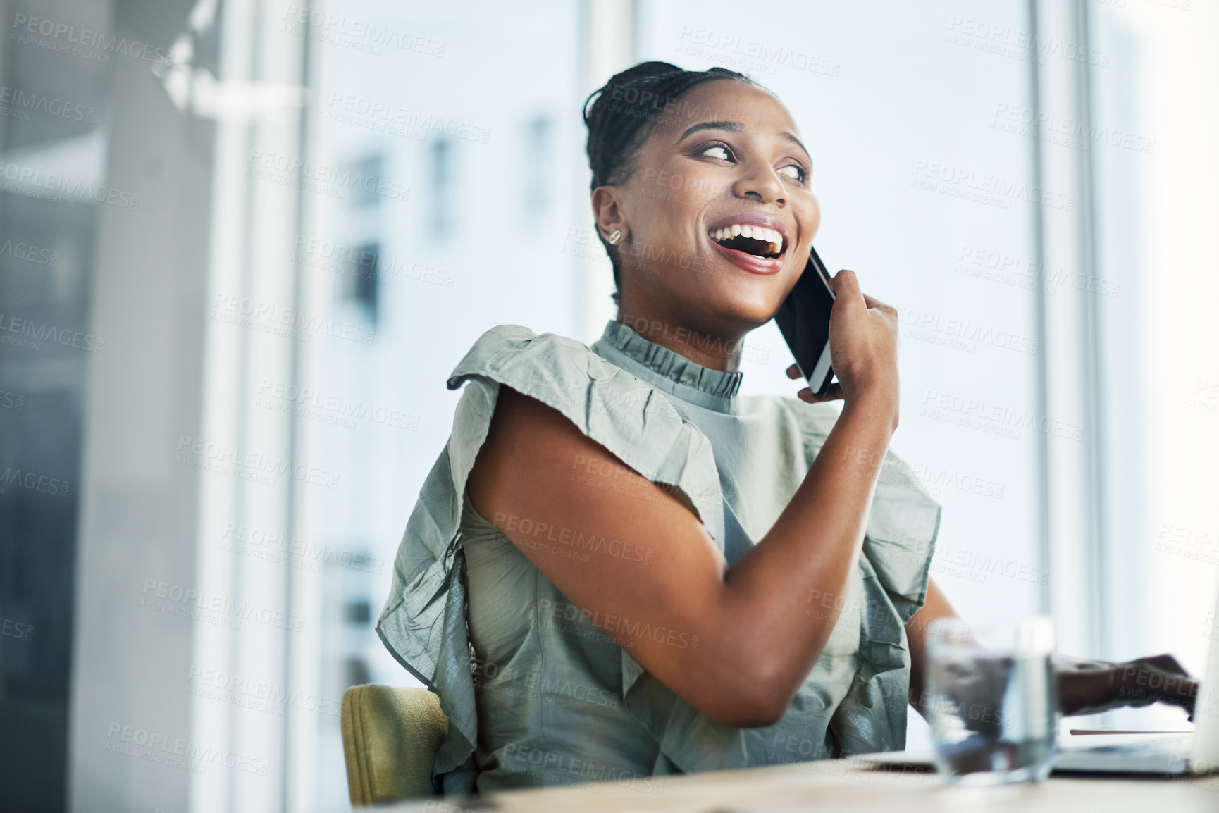 Buy stock photo Shot of an attractive young businesswoman sitting in the office and using her laptop while talking on her cellphone