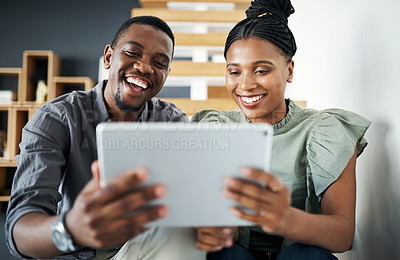 Buy stock photo Shot of two young businesspeople sitting together on a staircase in the office and using a digital tablet