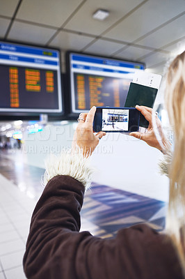 Buy stock photo Shot of a woman taking a photo of the time for her flight at the airport