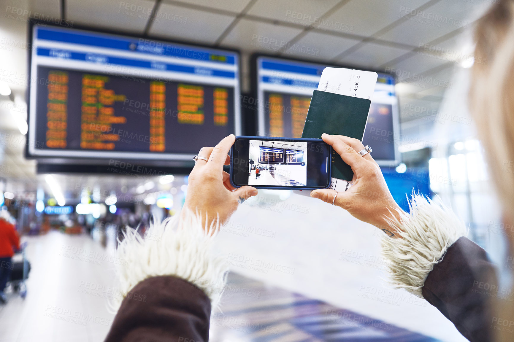 Buy stock photo Shot of a woman taking a photo of the time for her flight at the airport