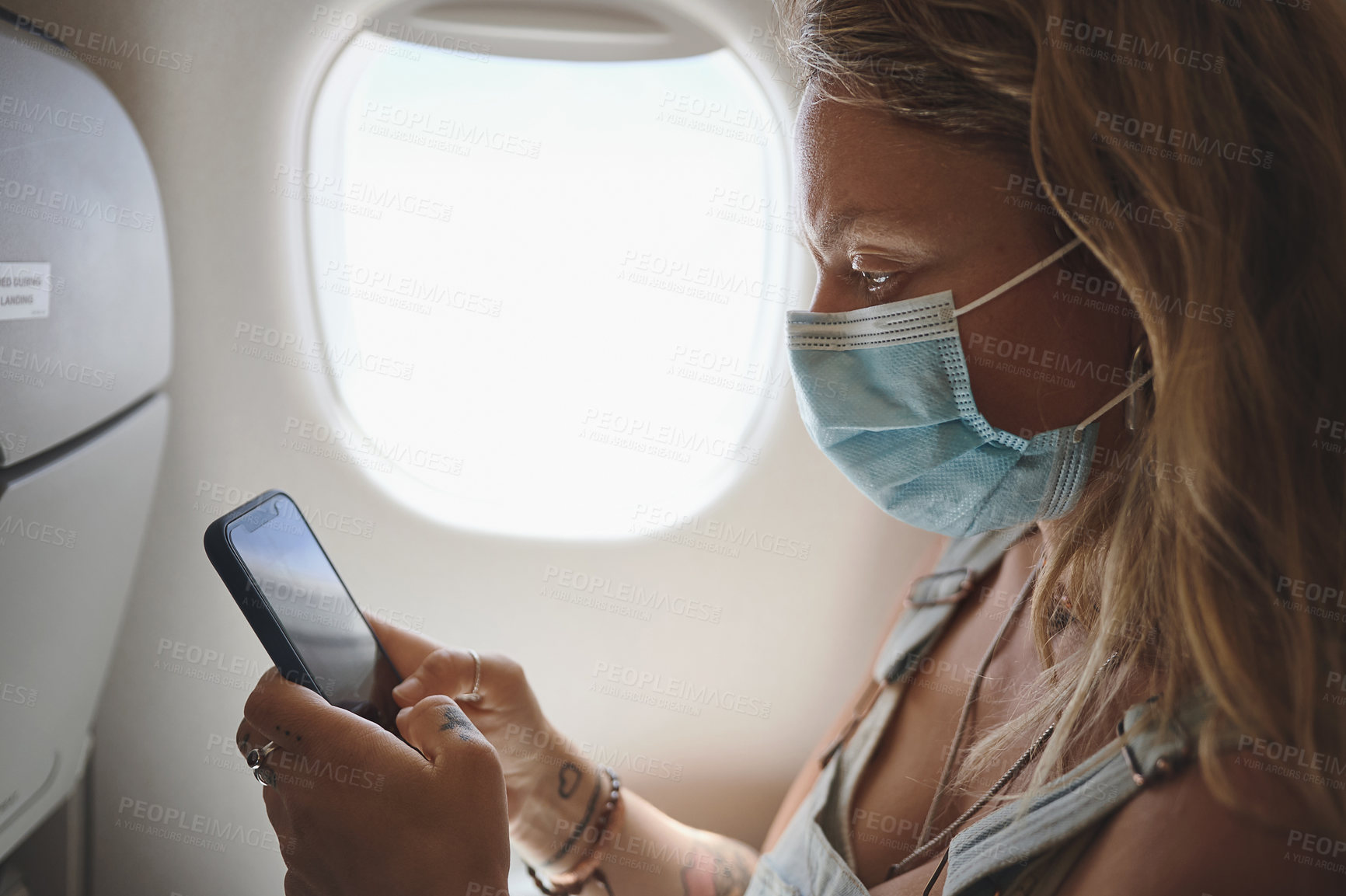 Buy stock photo Shot of a young woman using her phone in the aeroplane