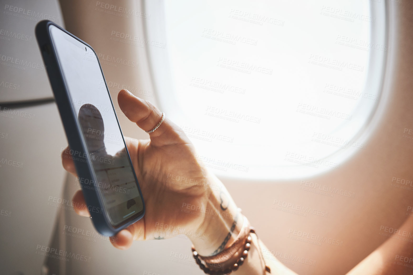 Buy stock photo Cropped shot of a woman using her phone in the aeroplane