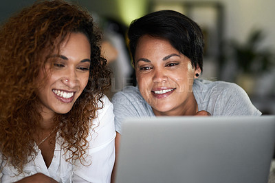 Buy stock photo Shot of a young couple using a laptop while lying on their bed