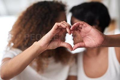 Buy stock photo Shot of an affectionate couple sitting together and forming a heart shape with their hands