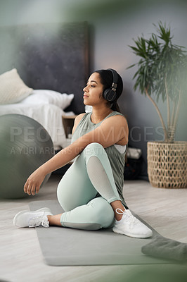 Buy stock photo Shot of a sporty young woman listening to music while exercising at home