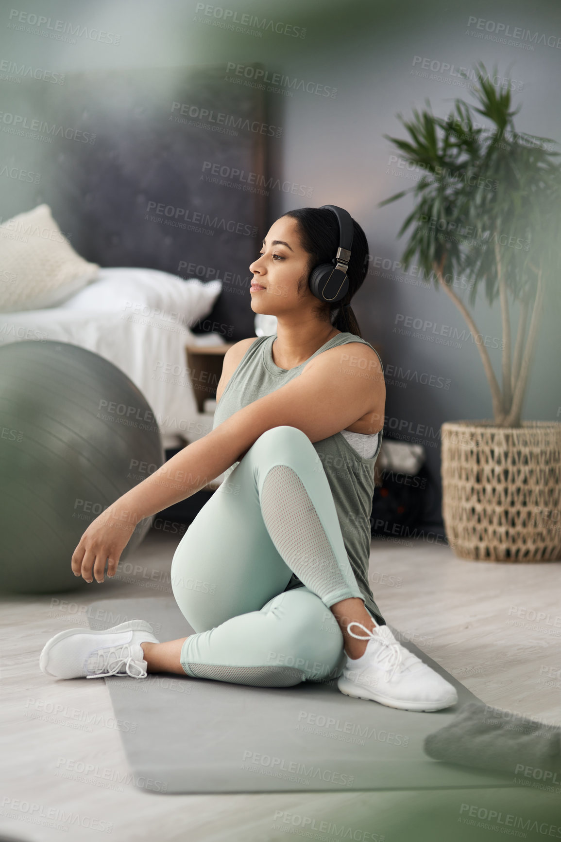 Buy stock photo Shot of a sporty young woman listening to music while exercising at home