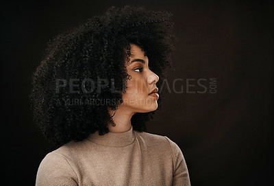 Buy stock photo Cropped shot of an attractive young woman looking thoughtful while posing in studio against a dark background