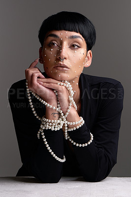 Buy stock photo Studio shot of a beautiful young woman with pearls on her face posing against a grey background