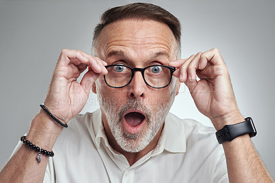 Buy stock photo Studio portrait of a mature man wearing spectacles and looking surprised against a grey background