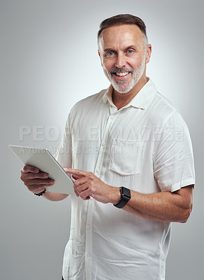 Buy stock photo Studio portrait of a mature man using a digital tablet against a grey background