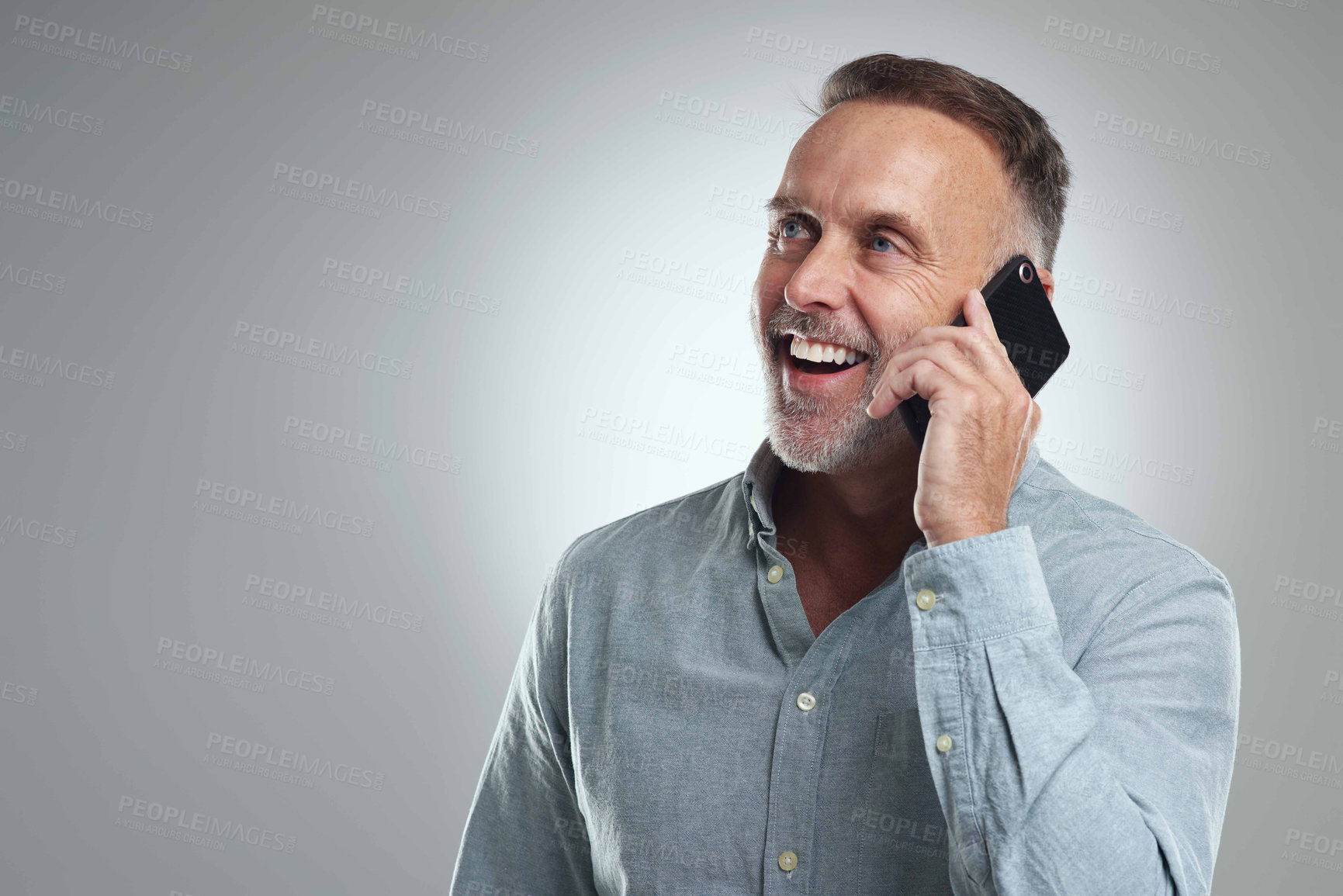 Buy stock photo Studio shot of a mature man talking on a cellphone against a grey background