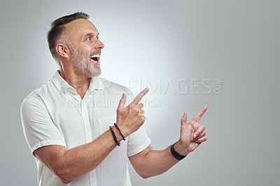 Buy stock photo Studio shot of a mature man pointing to copyspace against a grey background