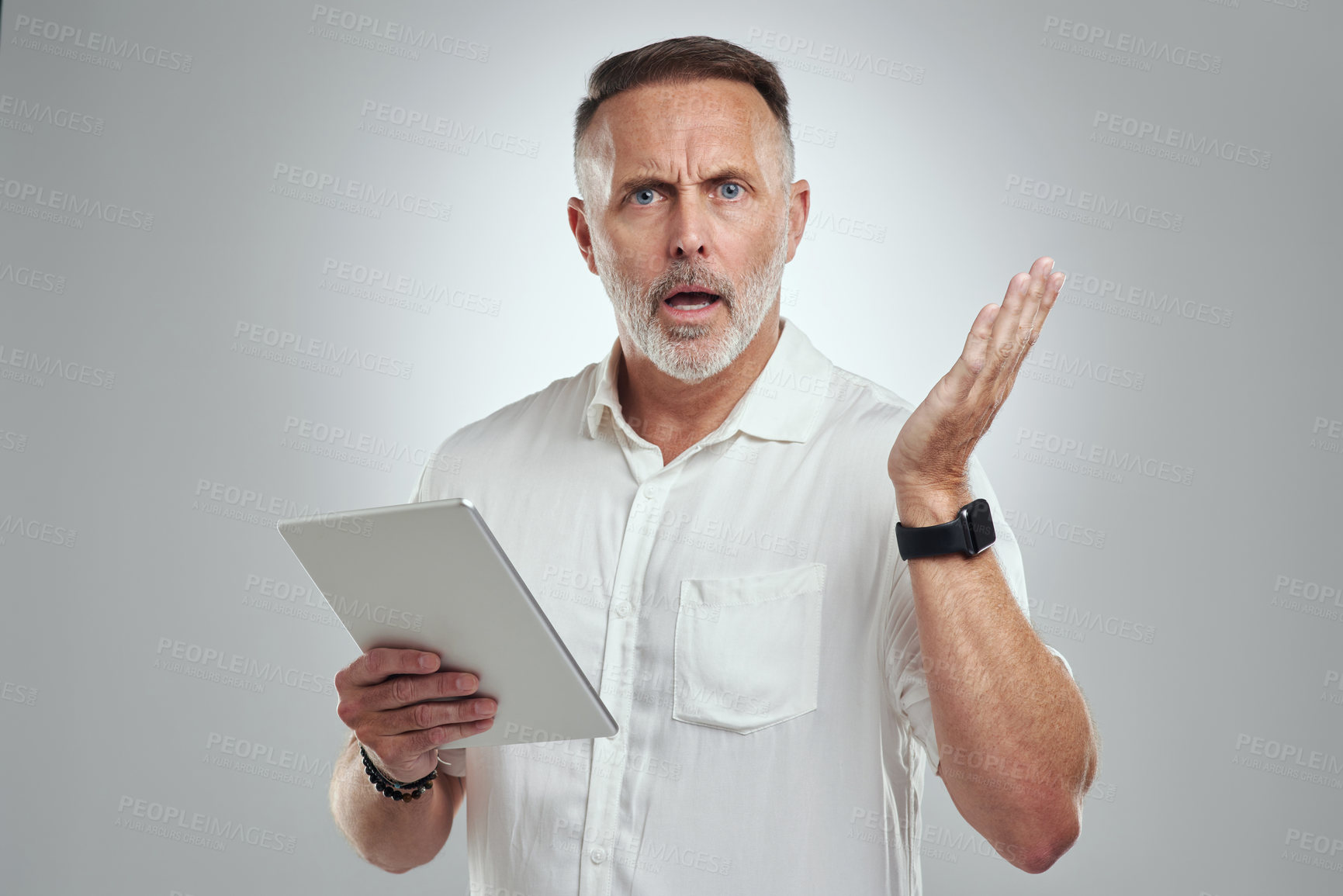 Buy stock photo Studio portrait of a mature man looking confused while using a digital tablet against a grey background