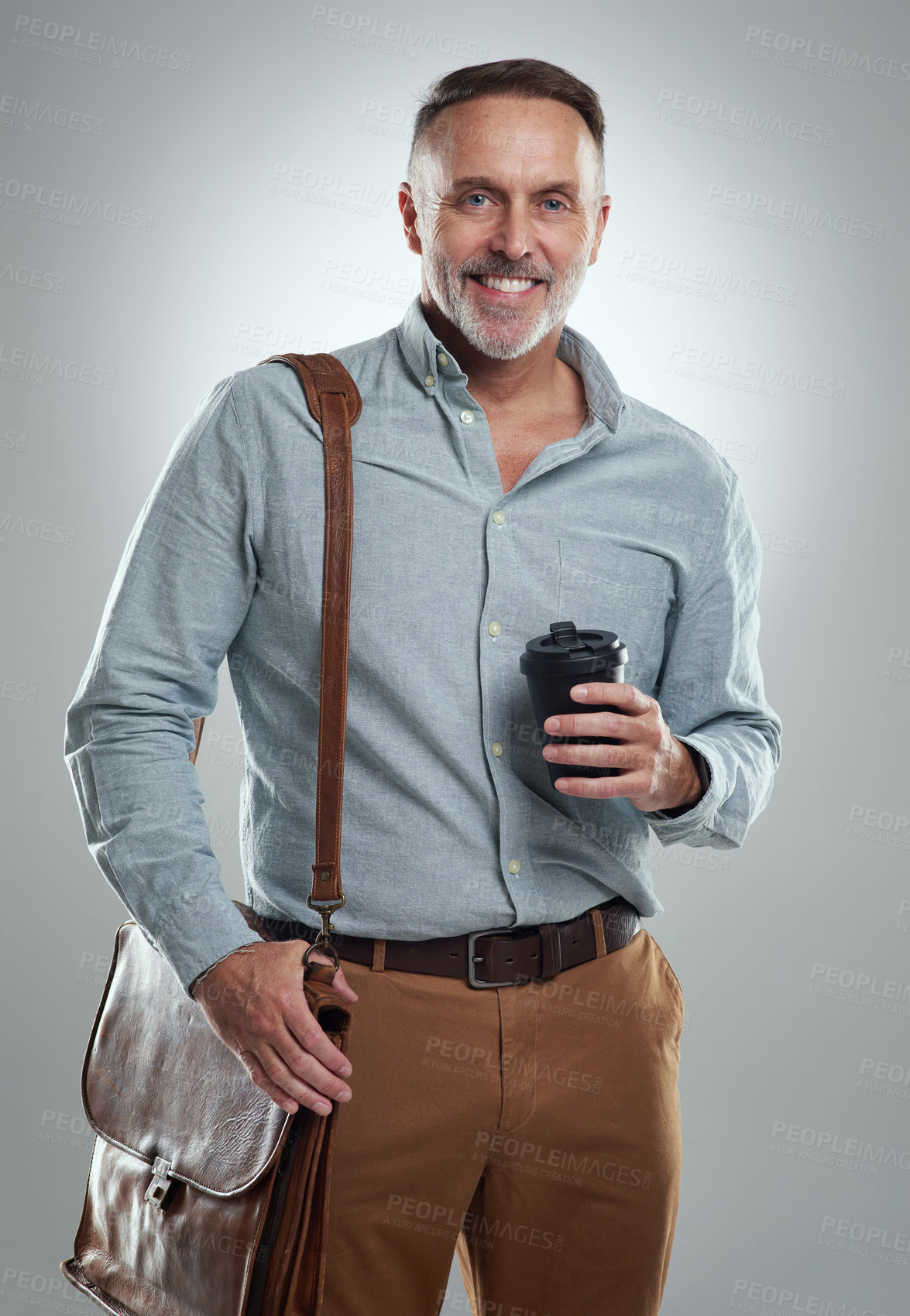 Buy stock photo Studio portrait of a mature man carrying a bag and cup of coffee against a grey background