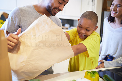 Buy stock photo Shot of a family unpacking the groceries in the kitchen at home