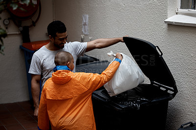 Buy stock photo Shot of a father and son putting newspaper in the bin to be recycled