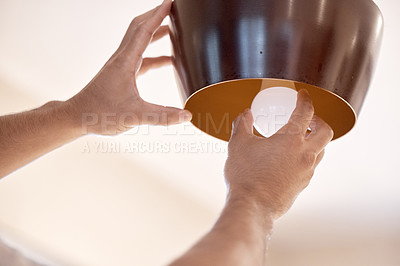 Buy stock photo Cropped shot of a unrecognizable man replacing a light bulb at home