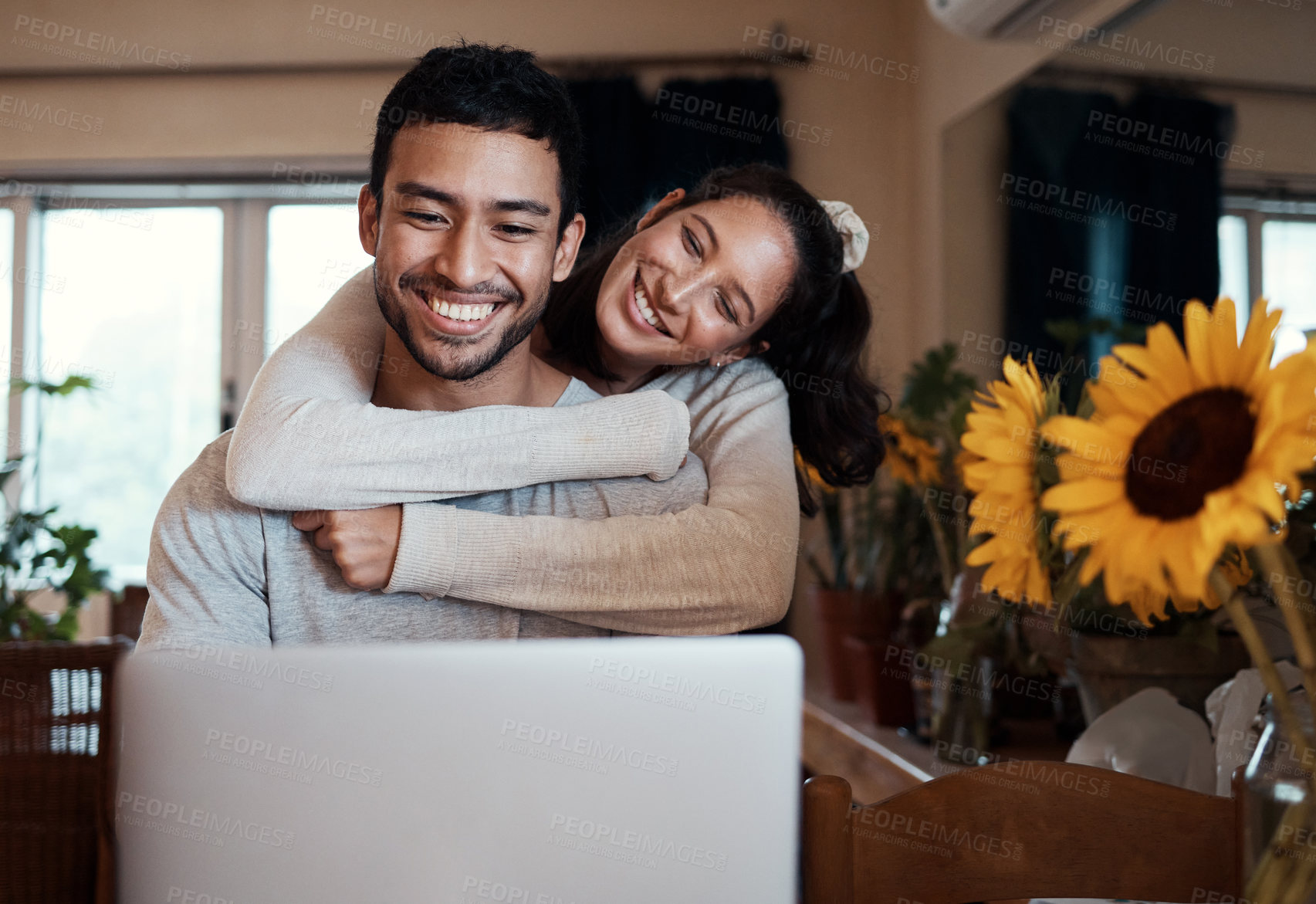 Buy stock photo Shot of a man using his laptop while his girlfriend embraces him from behind
