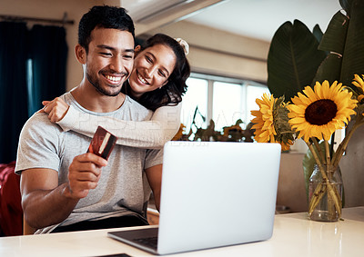Buy stock photo Shot of a man holding a credit card and using his laptop while at home with his girlfriend