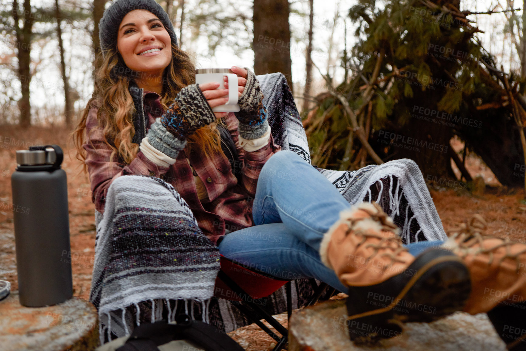 Buy stock photo Shot of a young woman drinking a warm beverage while camping in the wilderness during winter