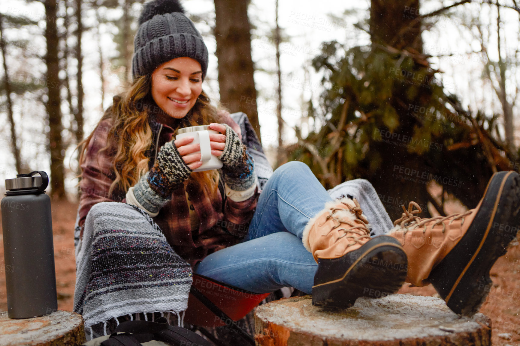 Buy stock photo Shot of a young woman drinking a warm beverage while camping in the wilderness during winter