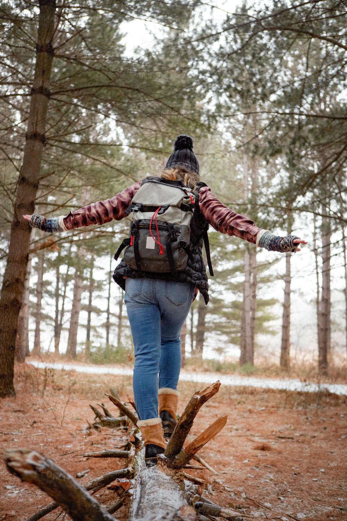 Buy stock photo Rearview shot of a young woman walking on a tree log in the wilderness during winter
