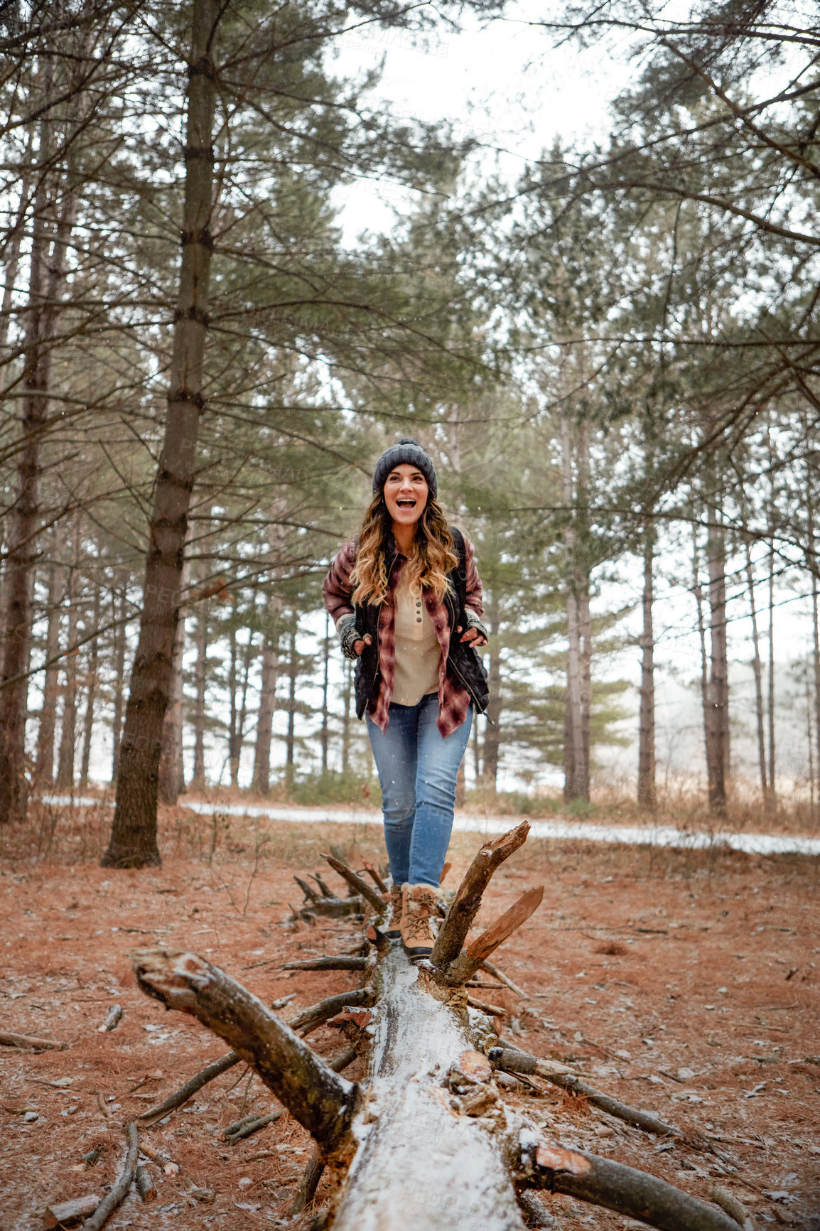 Buy stock photo Shot of a young woman walking on a tree log in the wilderness during winter