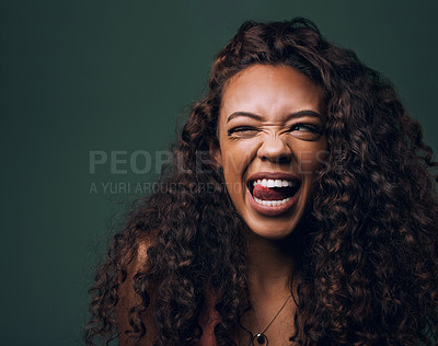 Buy stock photo Natural beauty, tongue out and wink by gen z girl with hair, curly and fun on green background. Afro, hair care and female model flirt, emoji and silly face, personality or youth aesthetic in studio