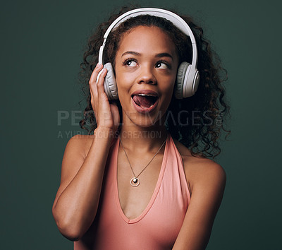 Buy stock photo Music, headphones and gen z girl in studio for streaming, silly face or audio on green background. Podcast and goofy female model relax while listening to radio, audio or online playlist