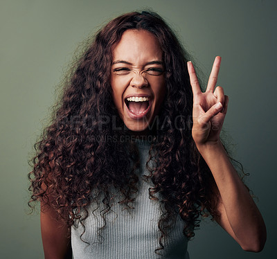 Buy stock photo Studio shot of a young woman making a peace gesture against a green background