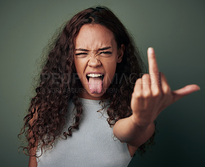 Buy stock photo Portrait, woman and middle finger sign with studio for expression or conflict, rebel and fuck you for opinion. Girl, isolated and green background with hand gesture for hate with tongue out and rude.