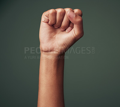Buy stock photo Studio shot of an unrecognisable woman raising her hand in strength against a green background