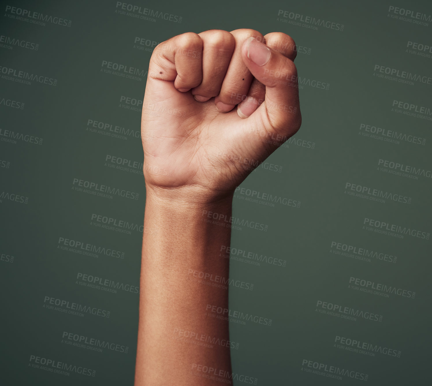 Buy stock photo Studio shot of an unrecognisable woman raising her hand in strength against a green background