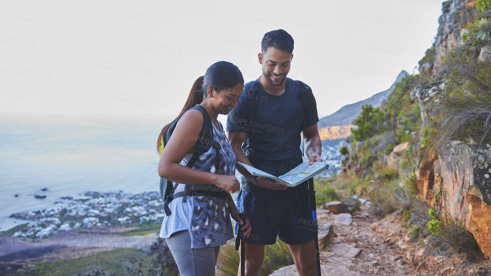 Buy stock photo Shot of a young couple using a guide book to complete a hike in a mountain range