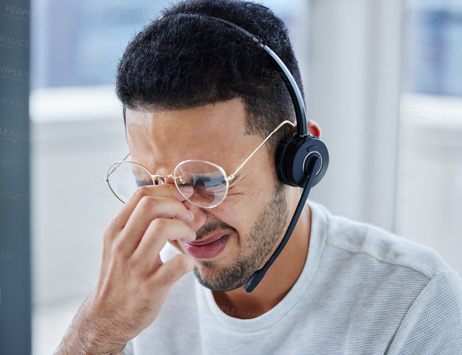 Buy stock photo Shot of a young businessman suffering s headache at his desk in his office