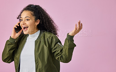 Buy stock photo Shot of an attractive young woman standing against a pink studio background and looking surprised while using her cellphone