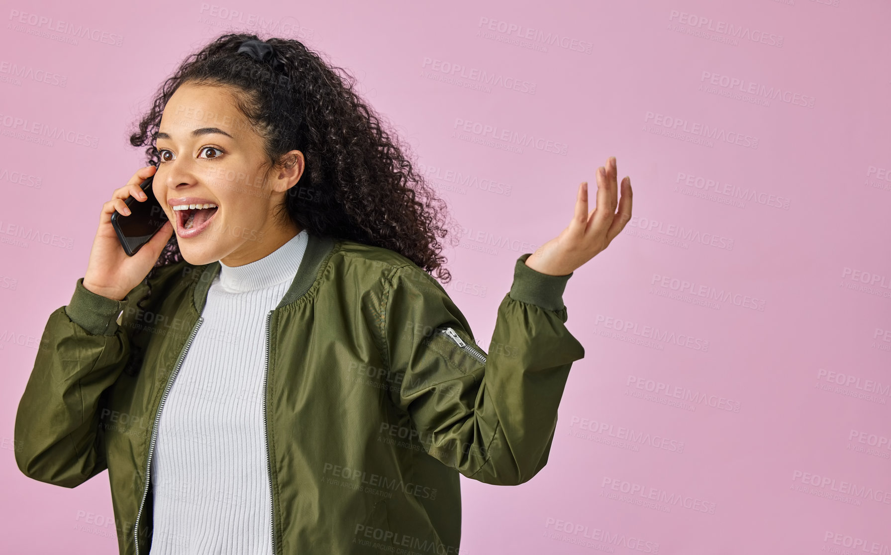 Buy stock photo Shot of an attractive young woman standing against a pink studio background and looking surprised while using her cellphone